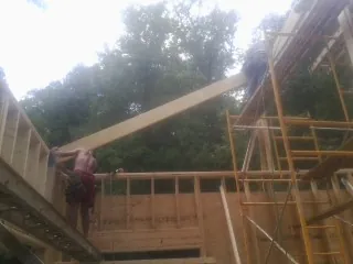 Carpenter raising a rafter beam on a new second story frame in Courtland